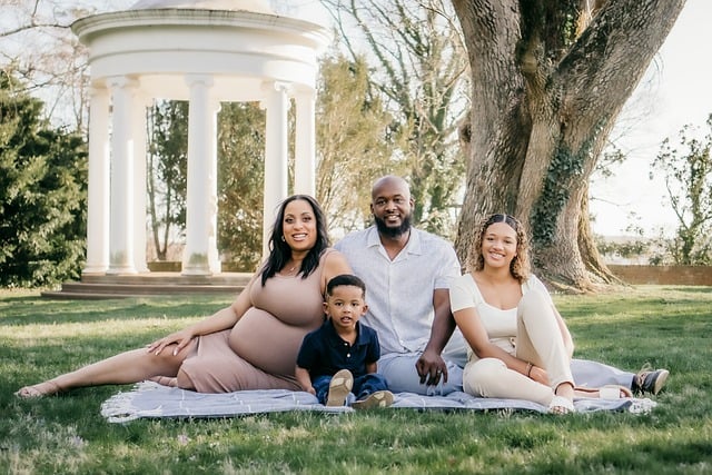 wholesome african american family sitting on the grass on top of a light blue blanket