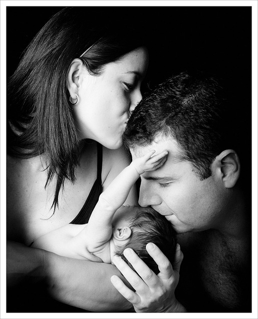 father kissing newborn baby on the head as mother kisses father on his head
