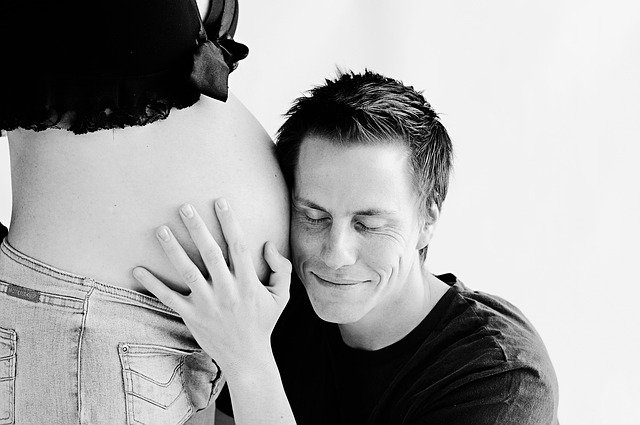 man with ear on pregnant belly