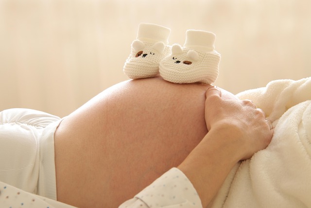 baby shoes placed on the skin of a pregnant belly
